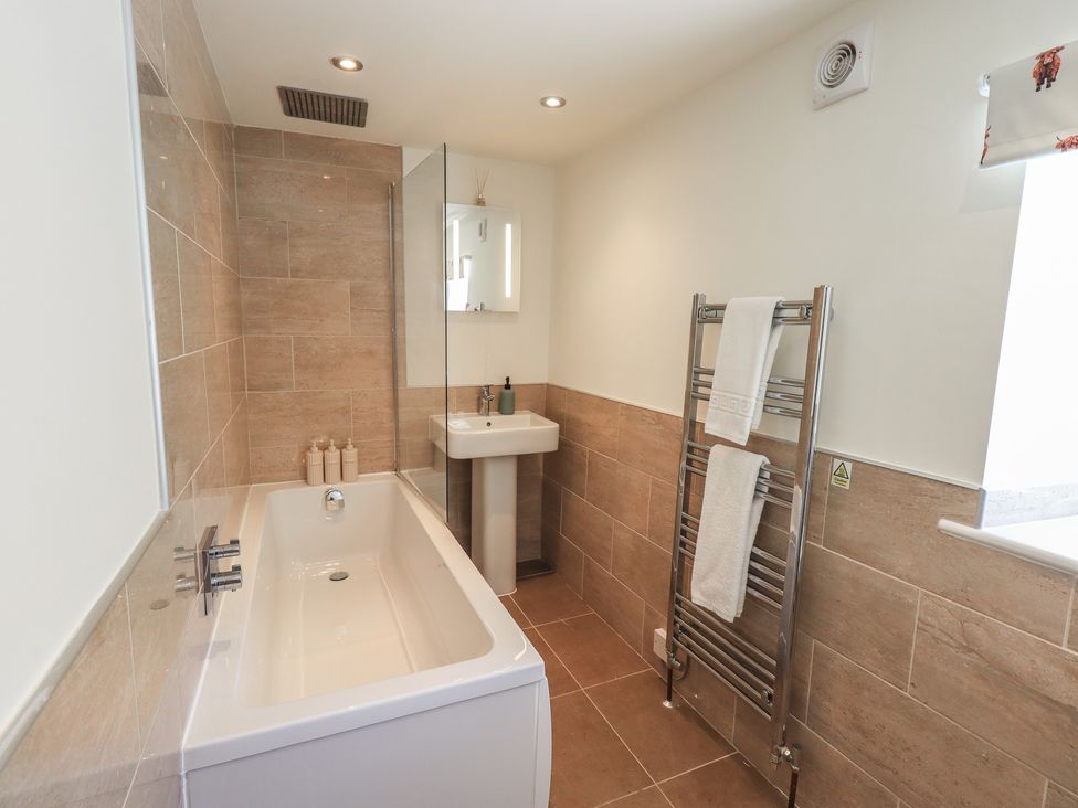 A bathroom featuring a bathtub, sink and towel rail at Fogga Croft in Gargrave
