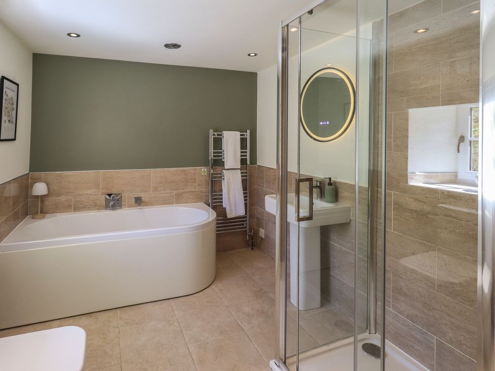 A bathroom with a bathtub, shower, sink and towel rail at Fogga Croft in Gargrave
