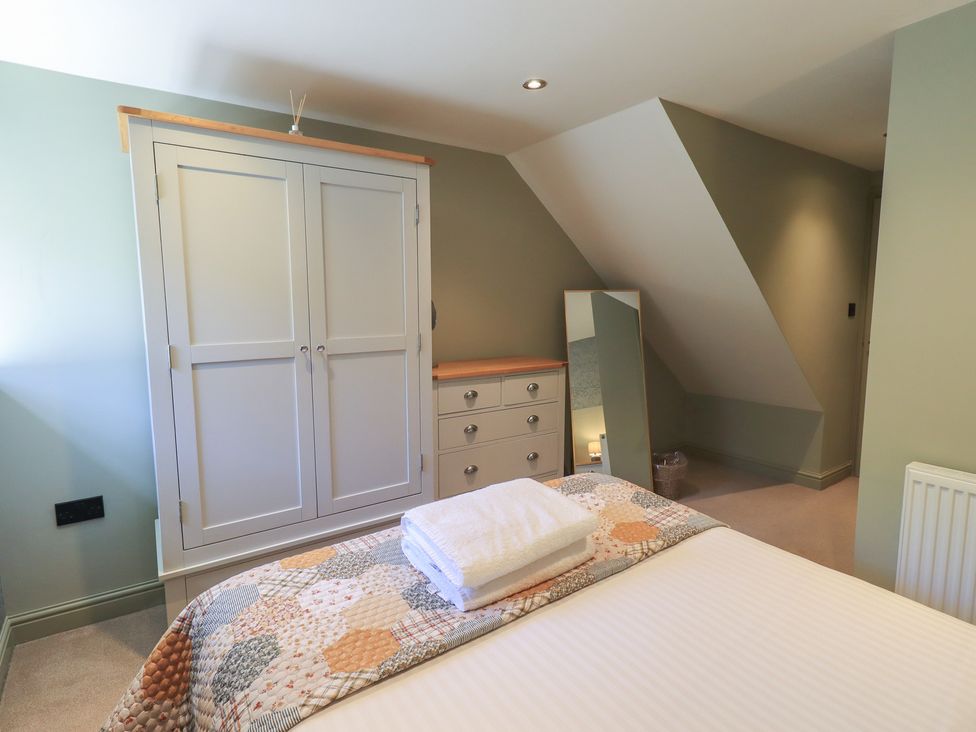 A bedroom with a bed, wardrobe, and mirror at Fogga Croft in Gargrave