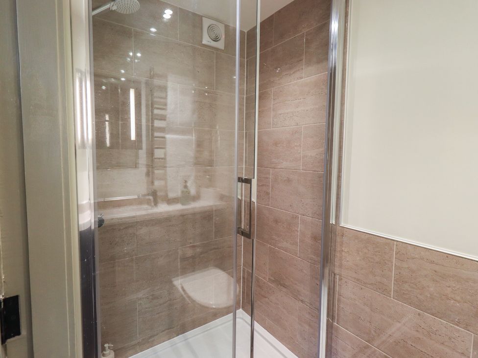 A shower with glass doors and tiles in a bathroom at Fogga Croft in Gargrave