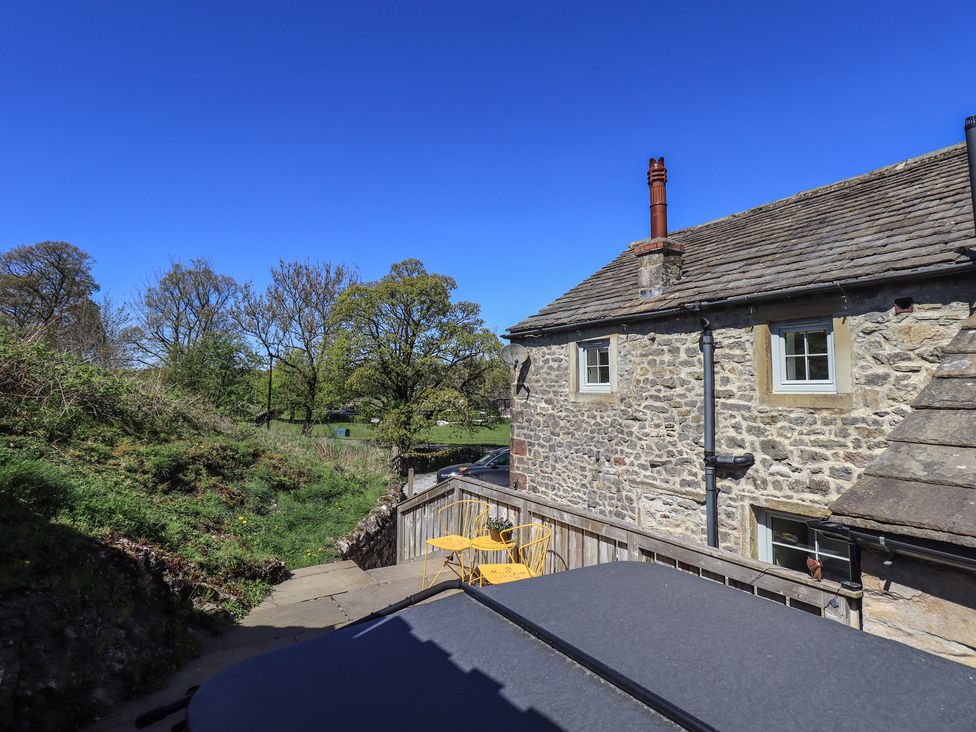 An outdoor view of a stone house with chairs and trees at Fogga Croft in Gargrave