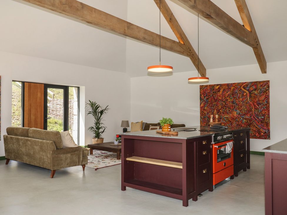 A living room with a kitchen island and sofa at Reddaway Threshing Barn near Okehampton