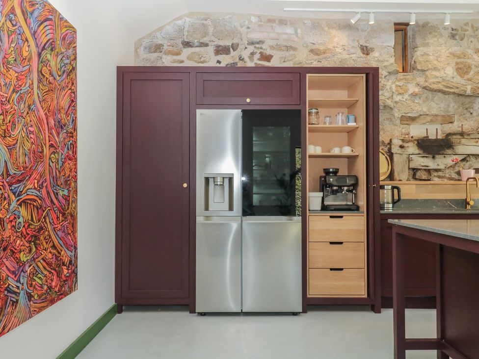 A kitchen with refrigerator and coffee maker at Reddaway Threshing Barn near Okehampton