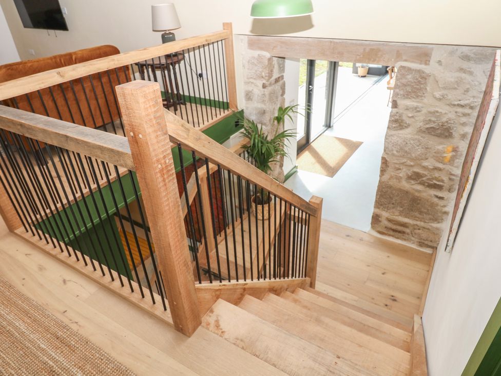 A staircase with a handrail and potted plant at Reddaway Threshing Barn near Okehampton