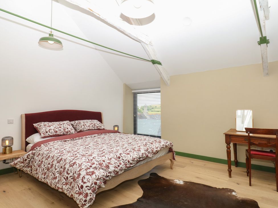 A bedroom with a bed and desk at Reddaway Threshing Barn near Okehampton