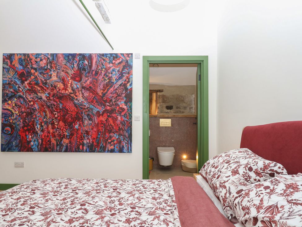 A bedroom with a bed and a bathroom entrance at Reddaway Threshing Barn near Okehampton