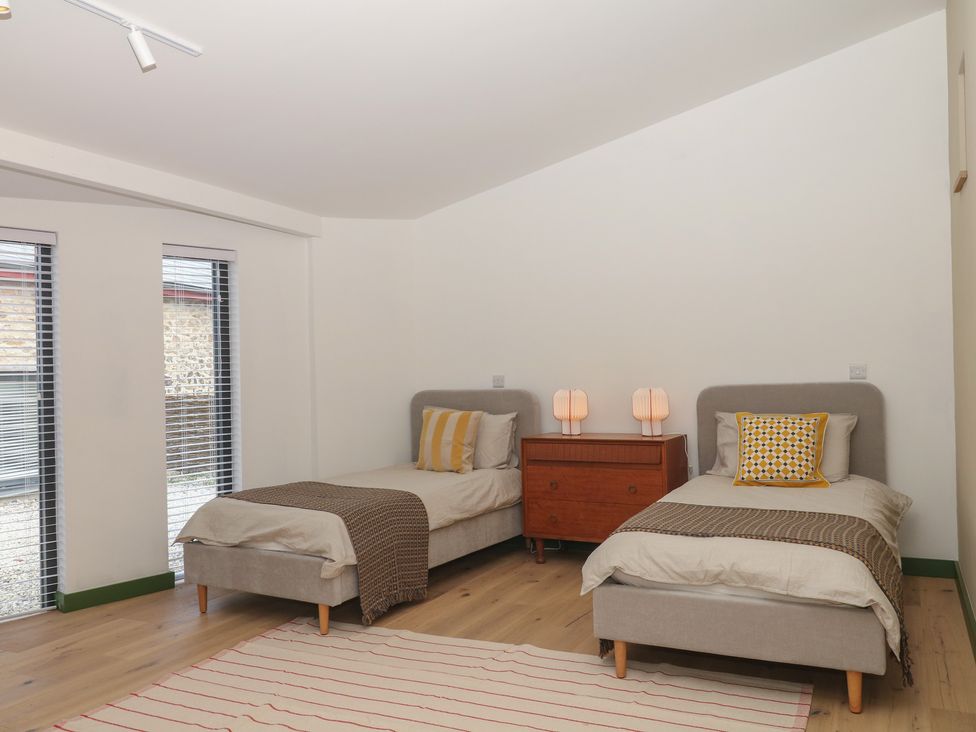 A bedroom with two beds and a bedside table at Reddaway Threshing Barn near Okehampton