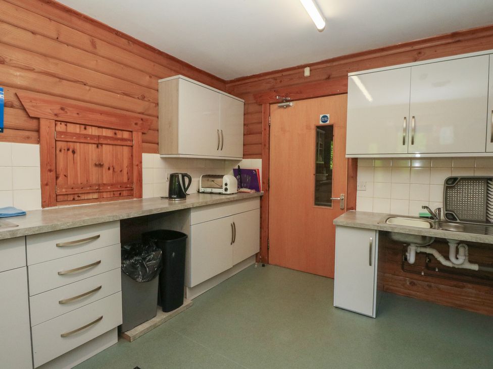 A kitchen with cabinets, a sink, and appliances at Shore Lodge in Brodick