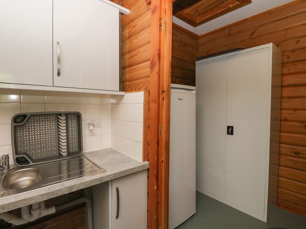 A kitchen with a sink, dish rack, and fridge at Shore Lodge in Brodick