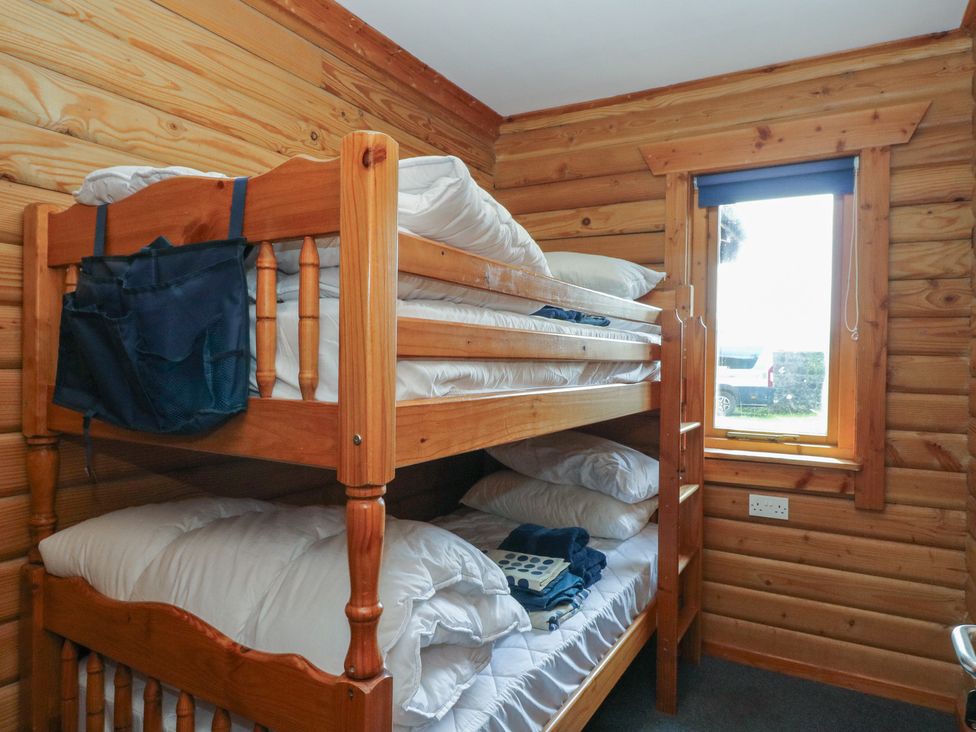 A bedroom with a bunk bed and window at Shore Lodge in Brodick