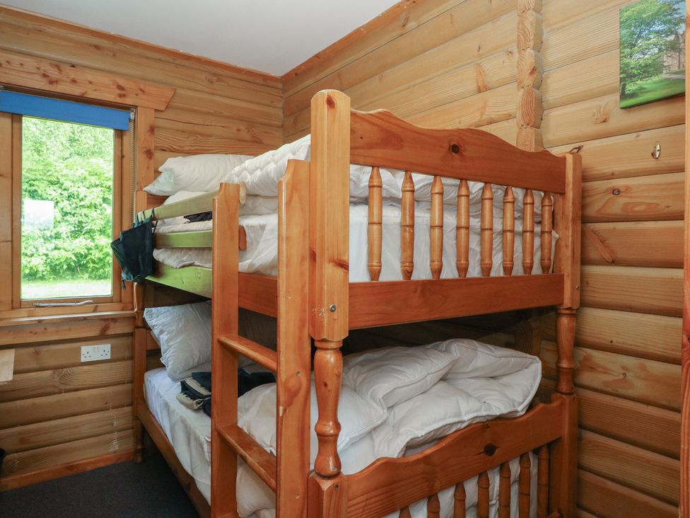 A bunk bed with bedding in a wooden room at Shore Lodge in Brodick