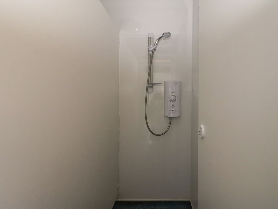 A shower with a wall and water heater at Shore Lodge in Brodick
