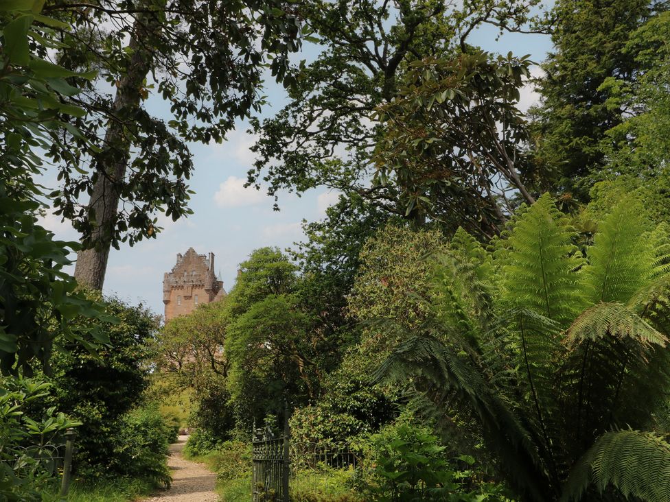 A pathway leading towards a castle surrounded by trees at Shore Lodge in Brodick