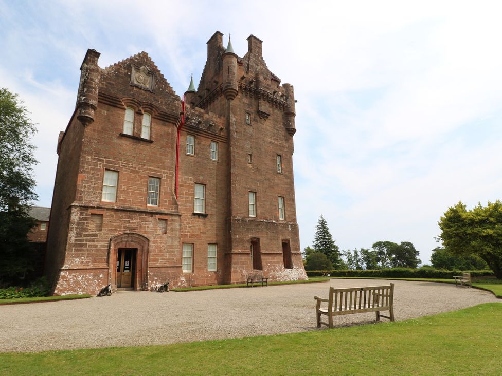 A castle with benches and trees in a garden at Shore Lodge Brodick
