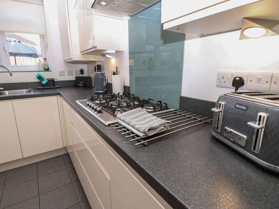 A kitchen with a counter, sink, cooker, and appliances at 50 Sea Road in Milford On Sea