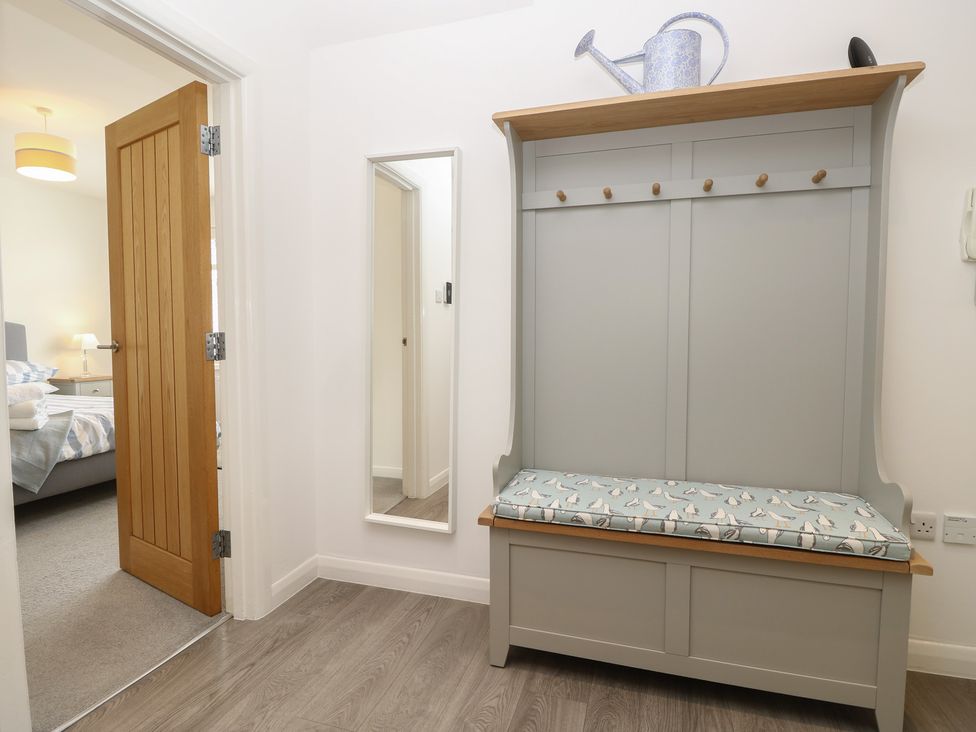 A hallway with a bench and coat hooks at 50 Sea Road in Milford On Sea
