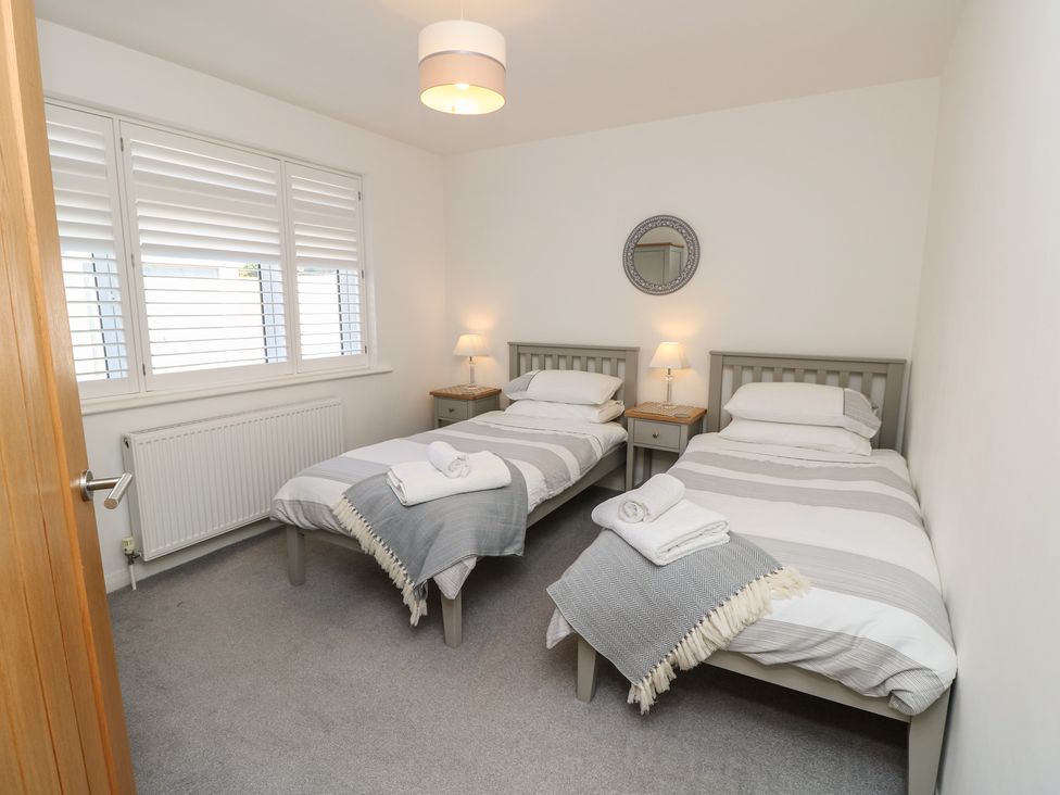 A bedroom with two beds and a nightstand at 50 Sea Road in Milford On Sea