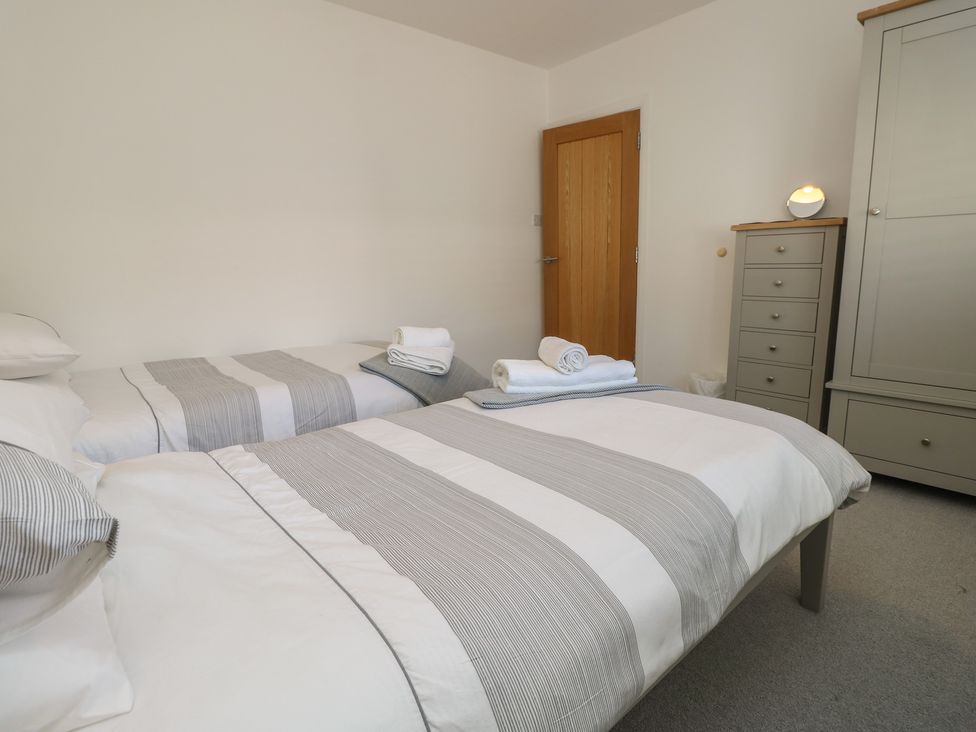 A bedroom with twin beds and a dresser at 50 Sea Road in Milford On Sea