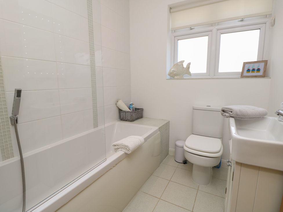 A bathroom with a bathtub, toilet, and sink at 50 Sea Road in Milford On Sea