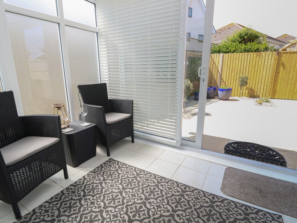 A conservatory with chairs and a table at 50 Sea Road in Milford On Sea