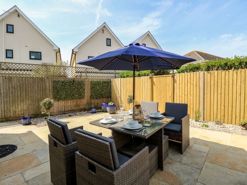 A garden with a table and chairs under a parasol at 50 Sea Road in Milford On Sea