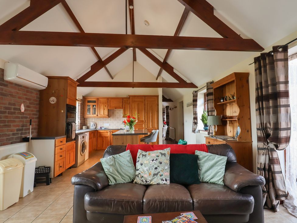 A living room with a sofa and kitchen area at Daisy Cottage in Whitchurch Canonicorum near Charmouth