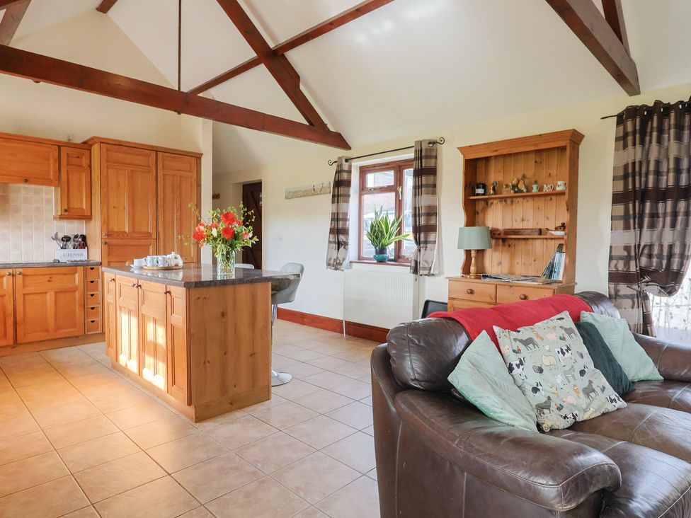 A kitchen with wooden cabinets and a sofa at Daisy Cottage in Whitchurch Canonicorum near Charmouth