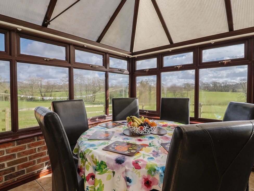 A dining table with chairs and windows in a conservatory at Daisy Cottage in Whitchurch Canonicorum near Charmouth