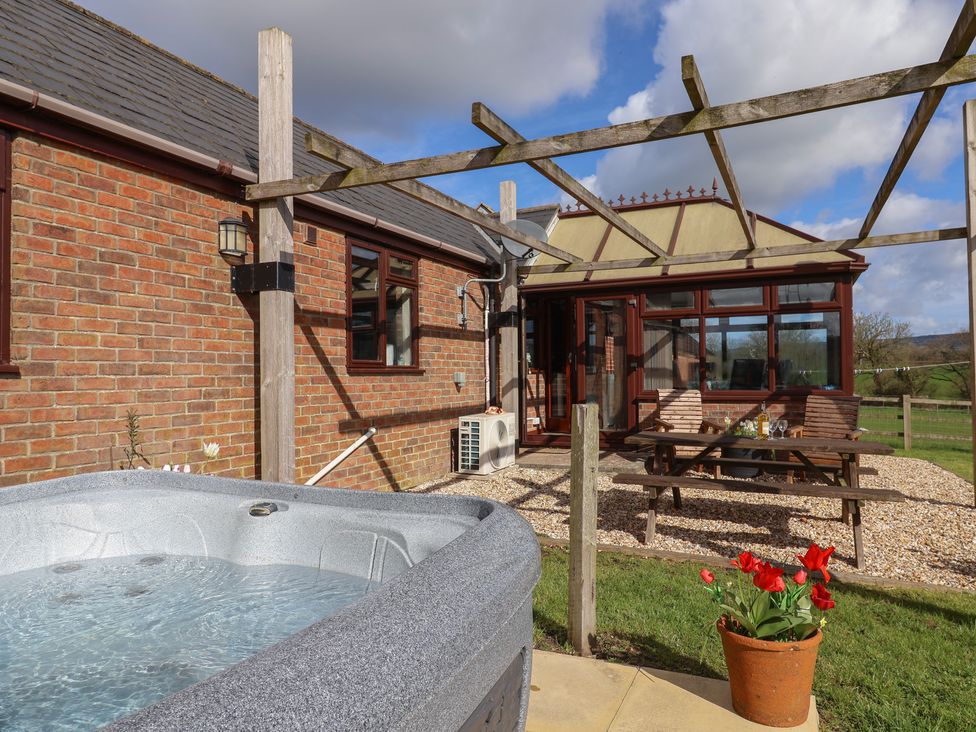 An outdoor area with a hot tub and table at Daisy Cottage in Whitchurch Canonicorum near Charmouth