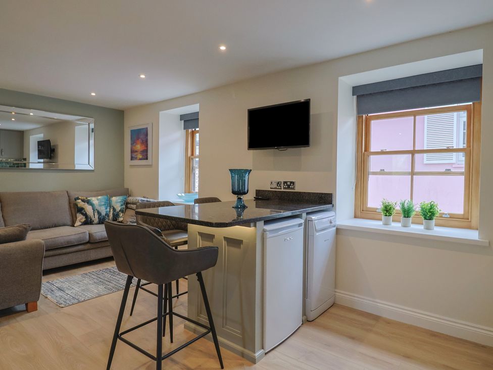 A living room with sofa and kitchenette at Flat 2 The Cedars in Lyme Regis