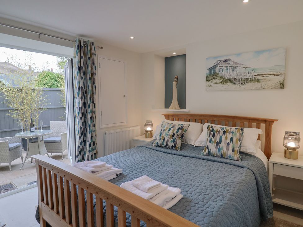 A bedroom with a bed and table at Flat 2 The Cedars in Lyme Regis