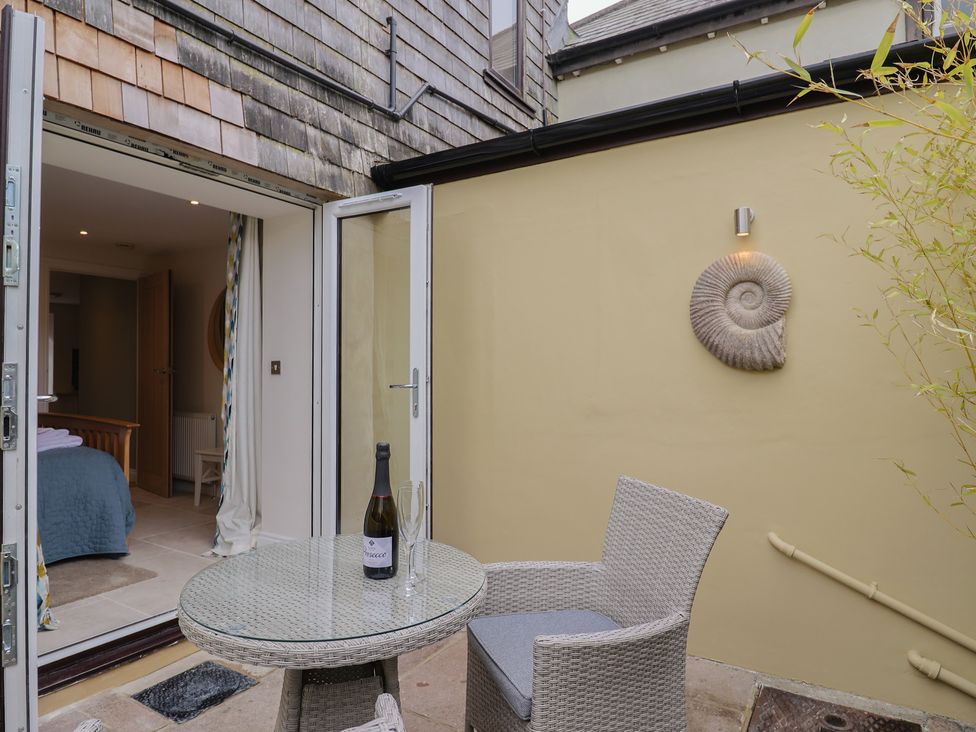 An outdoor area with a table and chairs and a bottle on the table at Flat 2 The Cedars Lyme Regis