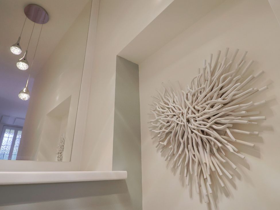 A hallway with a wall decoration and ceiling lights at Flat 2 The Cedars Lyme Regis