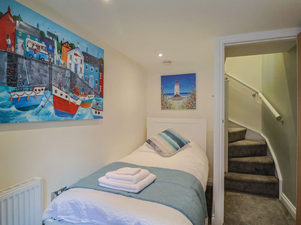 A bedroom with a single bed and paintings on the wall at Flat 2 The Cedars in Lyme Regis