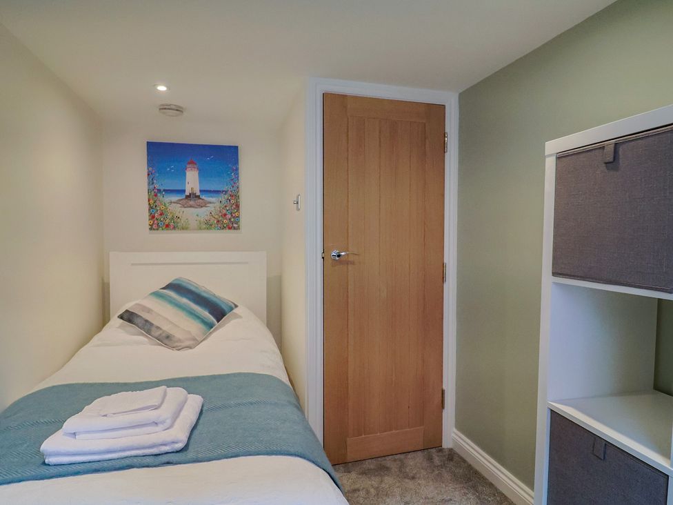 A bedroom with a single bed and a shelf unit at Flat 2 The Cedars Lyme Regis