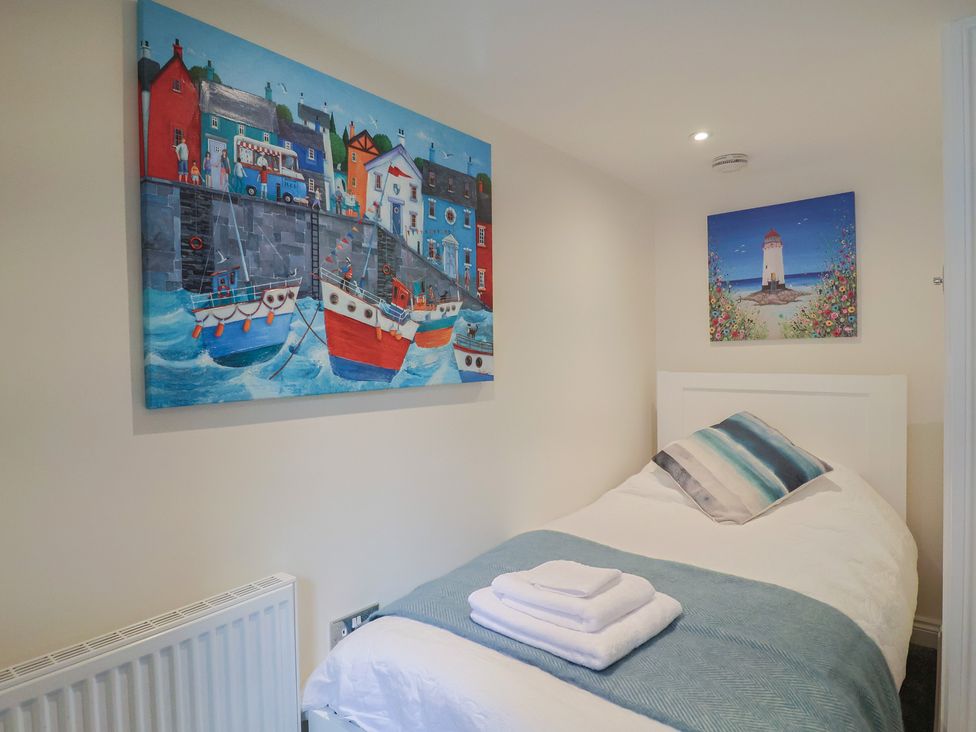 A bedroom featuring a single bed and wall art at Flat 2 The Cedars in Lyme Regis