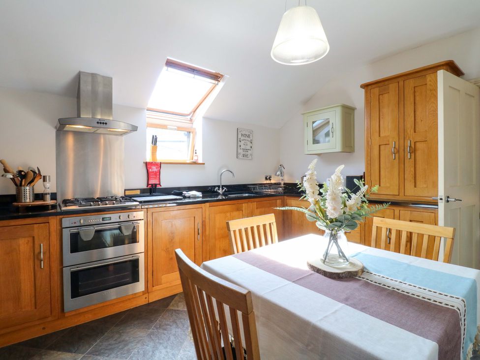 A kitchen with a stove, oven, sink, and wooden table at 2A Water Street Bakewell