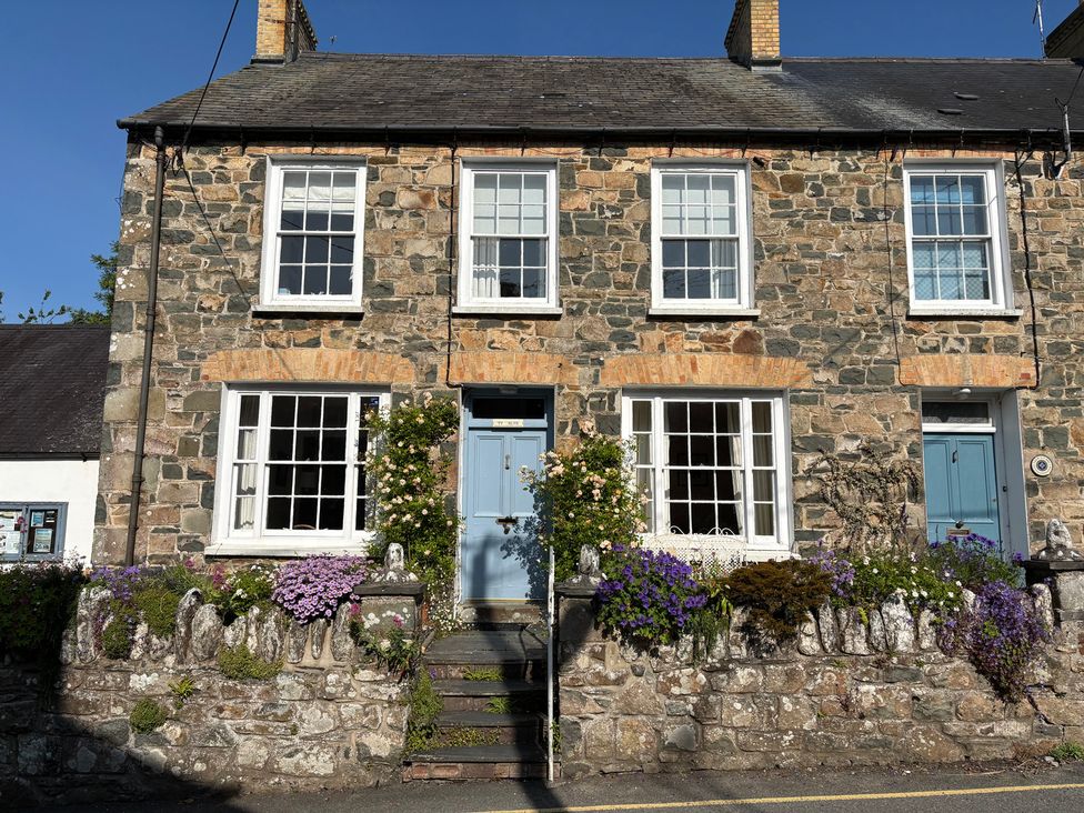 A stone house with a blue door and flower pots at Ty Clyd in Newport, Pembrokeshire