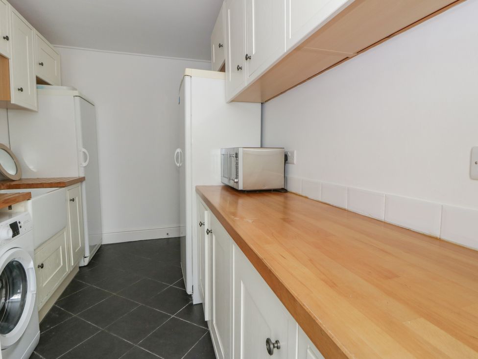 A laundry room with a washing machine and refrigerator at Ty Clyd Newport, Pembrokeshire