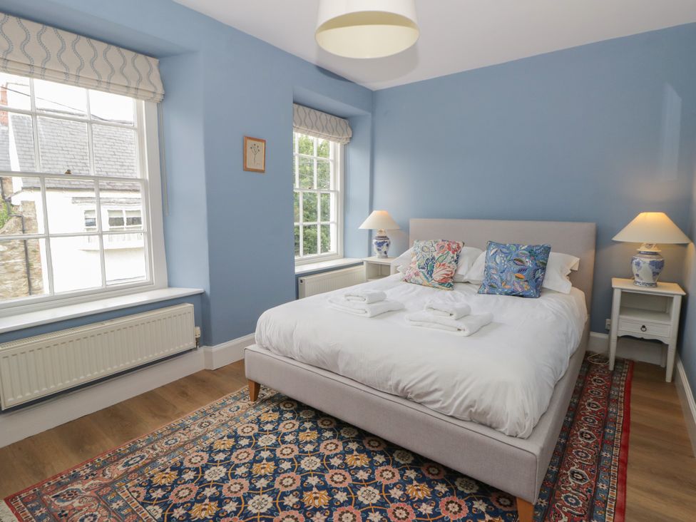 A bedroom with a bed and windows at Ty Clyd in Newport, Pembrokeshire