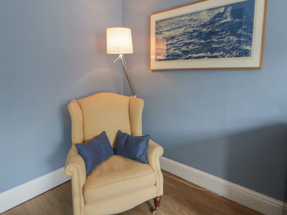 A living room with an armchair and lamp at Ty Clyd in Newport, Pembrokeshire