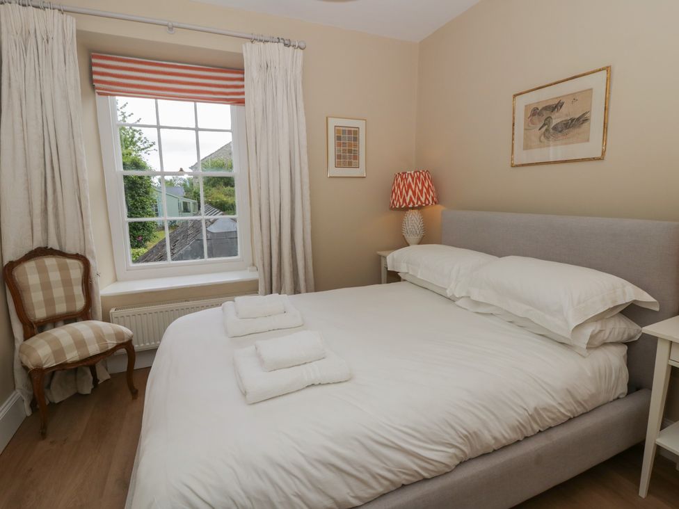 A bedroom with a bed, chair, and window at Ty Clyd in Newport, Pembrokeshire