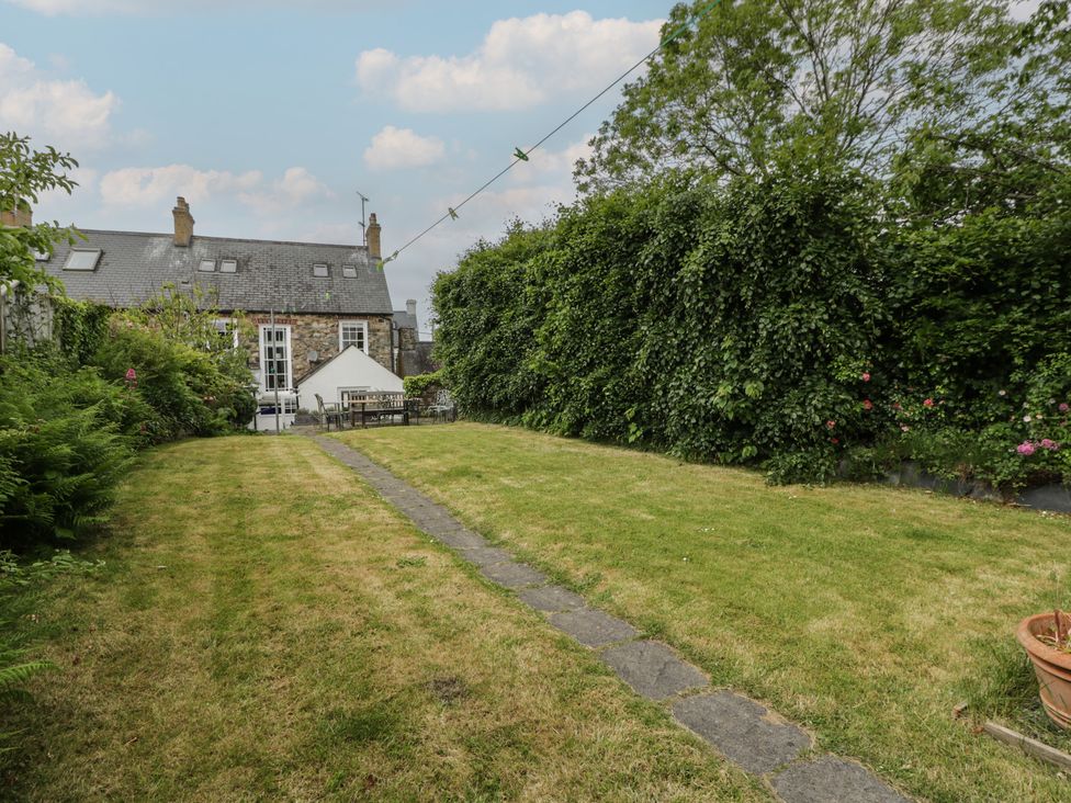 A garden with a grassy area and a stone path at Ty Clyd in Newport, Pembrokeshire