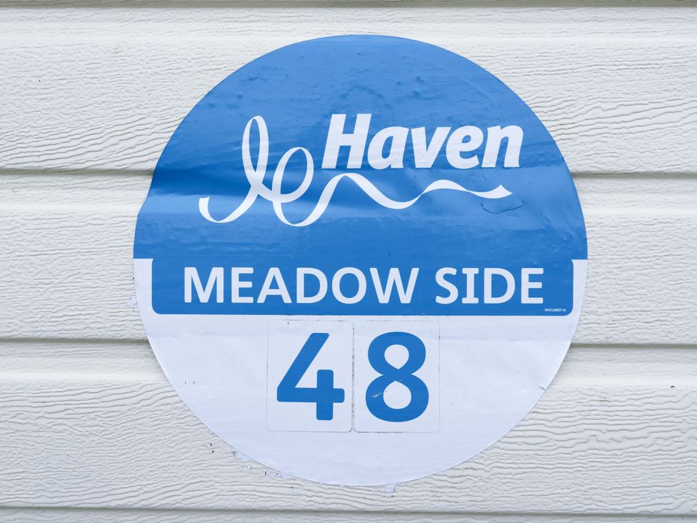 A sign for Meadow Side 48 with Haven logo on a wall