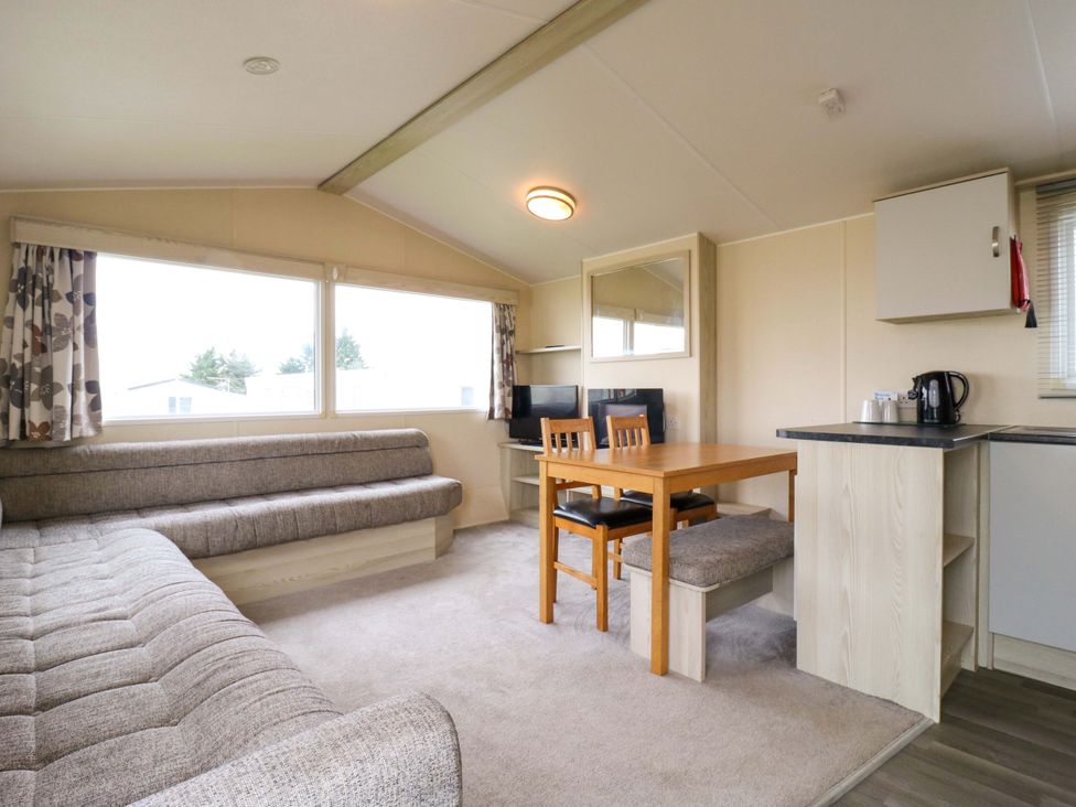 A living room with a sofa, table, chairs and television at Meadowside