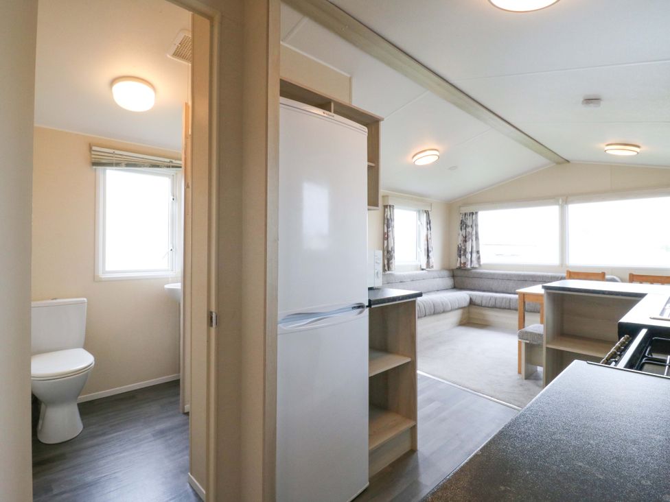 A living room with a sofa and kitchen area at Meadowside