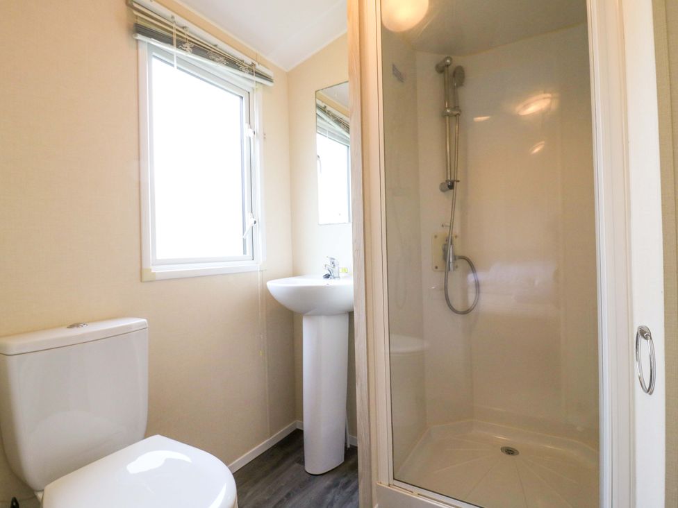 A bathroom with a toilet, sink, and shower at Meadowside