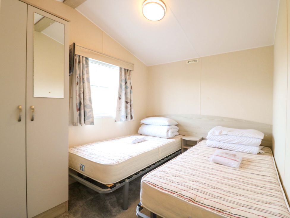 A bedroom with two beds and a wardrobe at Meadowside
