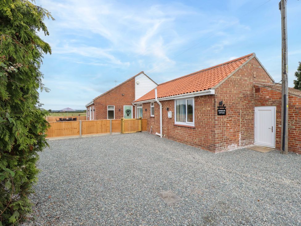 An outdoor area with a cottage and gravel driveway at Denholme in Hogsthorpe