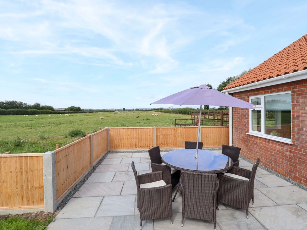 A patio area with a table and chairs at Denholme in Hogsthorpe